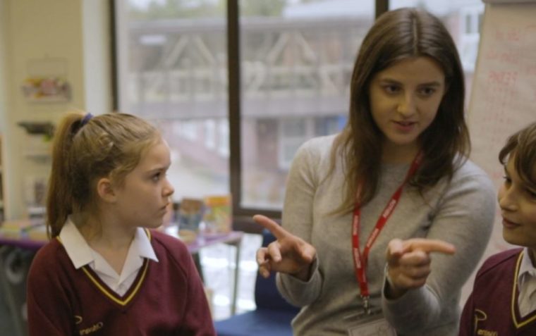 A teacher giving instructions to her two pupils while they carefully listen to her