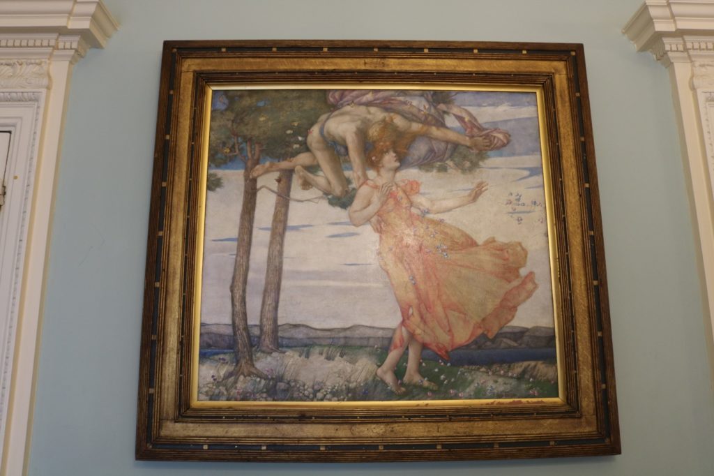 A picture of a painting hanging on a wall inside a building. 