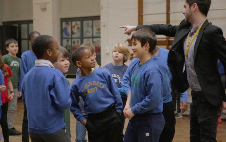 ESU Discover Your Voice teacher giving instructions to his students while they joyfully listen to him