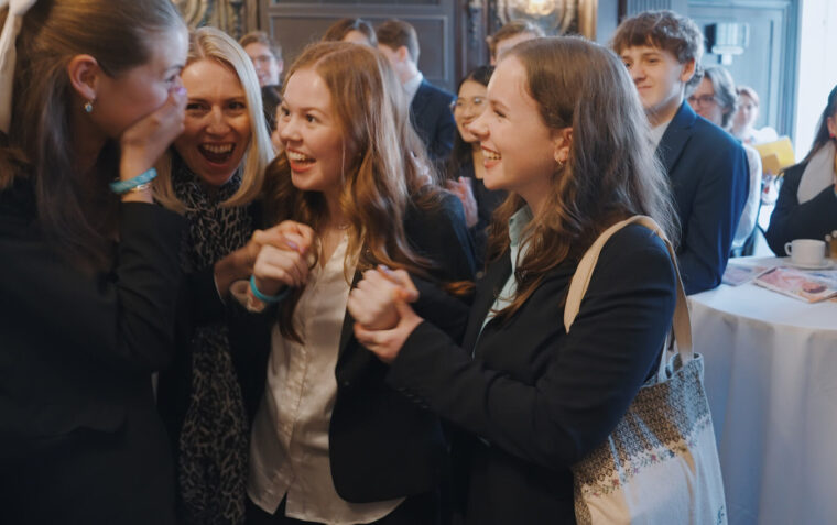 Four white female students smiling and laughing in a small group.