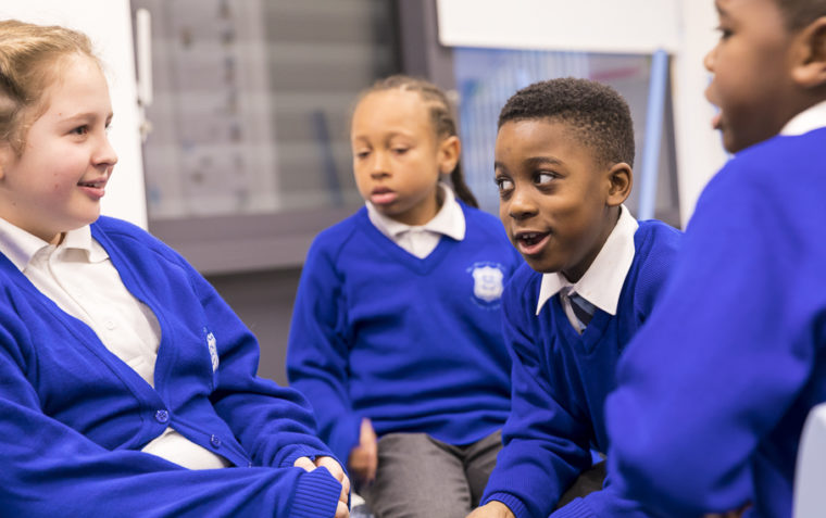 Four pupils (two boys and two girls) of St Mary’s Roman Catholic Primary School in Battersea sitting inside a classroom.