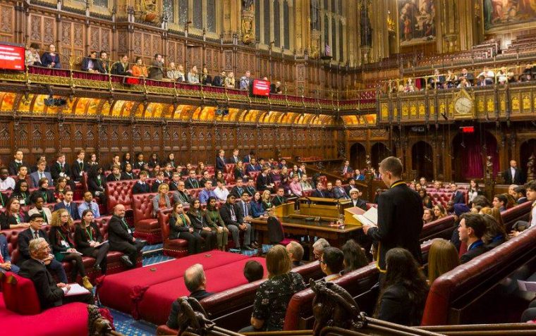 A young pupil delivering a speech at the House of Commons while her peers watch and listen
