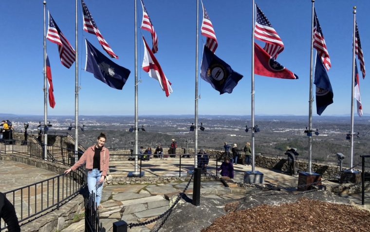 A photo of Emma Robinson on a mountain hill with a lot of flags in the background