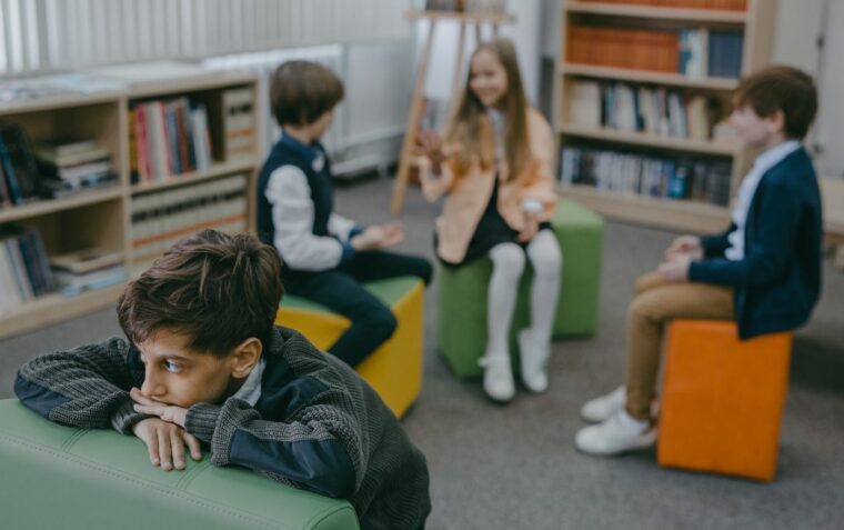 A group of 3 students socialising while the 4th pupil is isolated from them