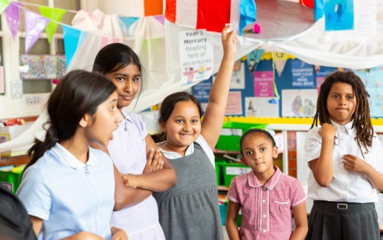 A group of students in a classroom with all looking enthusiastic