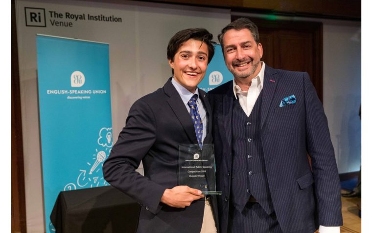 A young pupil posing with his award at the International Public Speaking Competition