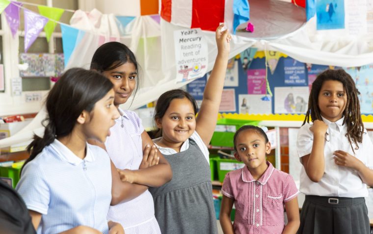 Five girls' pupils of Broadwater Primary School in Tooting, South London standing inside a classroom.